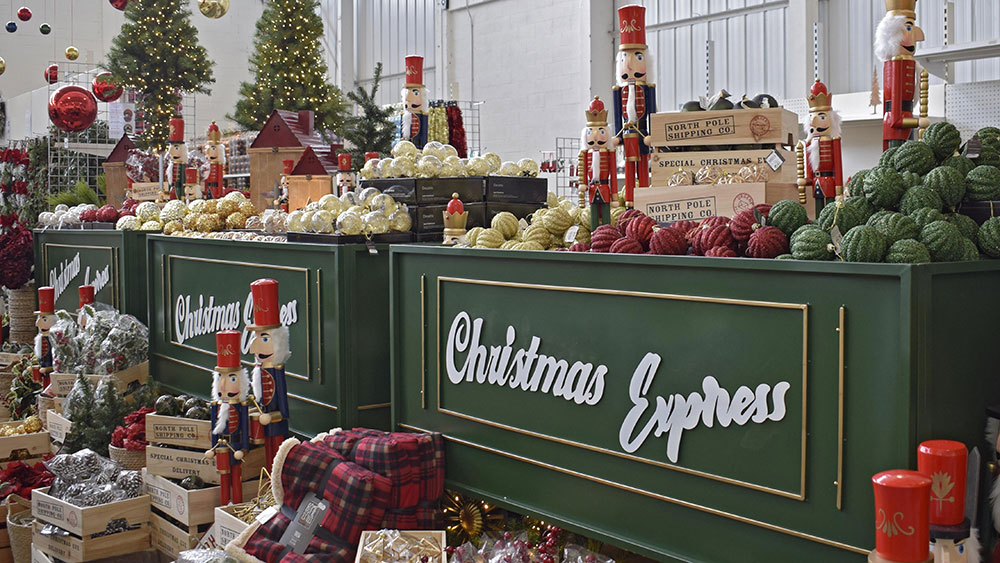 green christmas express display train filled with wooden crates, nutcracker figures, red checked blankets, and santas workshop decorations