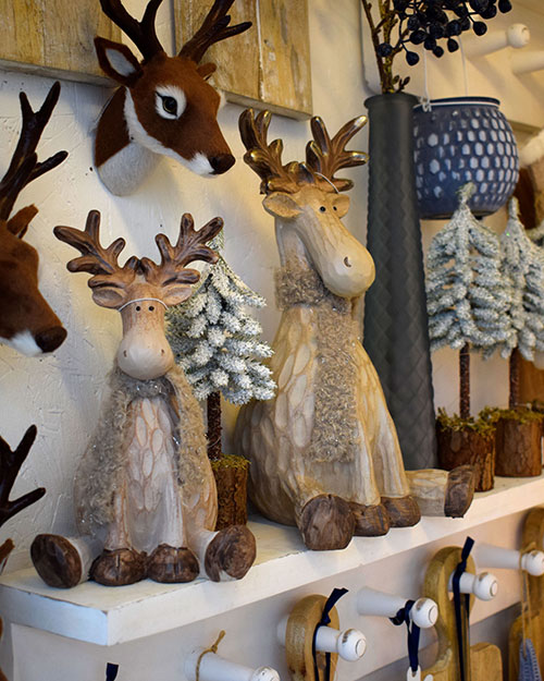 wooden and fabric reindeer figures and snowy tree ornaments on shelf