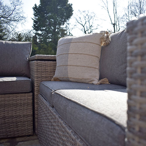 close up of grey seat on rattan garden furniture with beige cushion