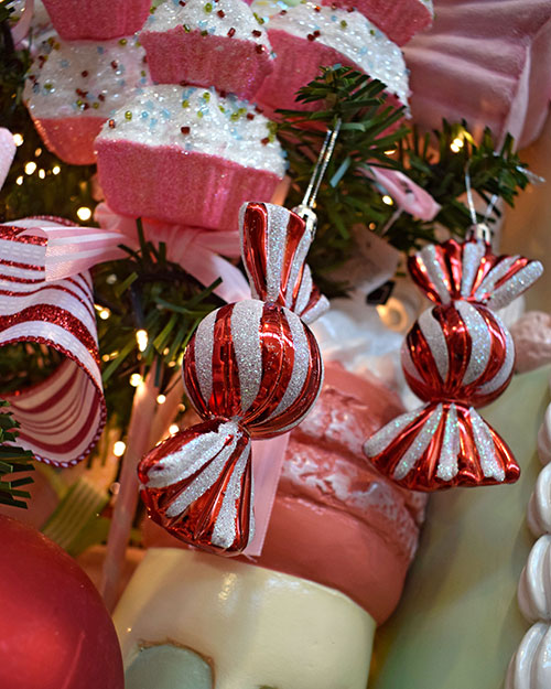 red and white sweet decorations in wrappers, pink and white cupcake Christmas decorations hanging on tree