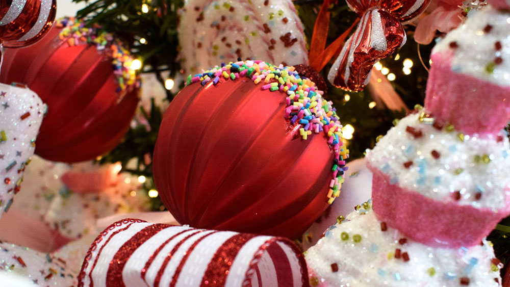 close up of red ribbed bauble with hundreds and thousands and pink and white cupcake christmas decoration