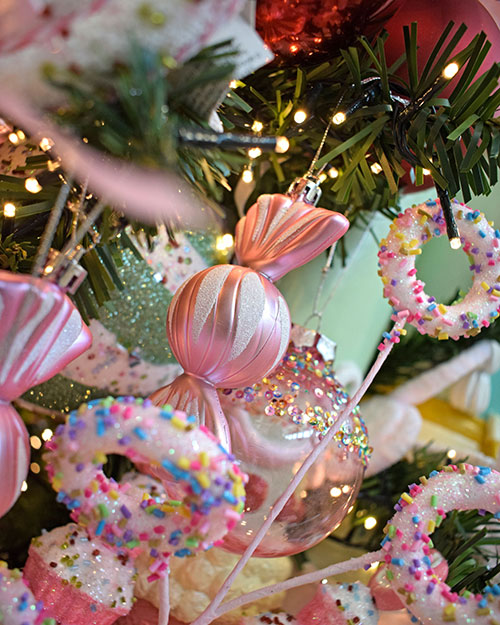 close up of pink and green sweet themed christmas decorations and doughnut shaped decorations on sticks