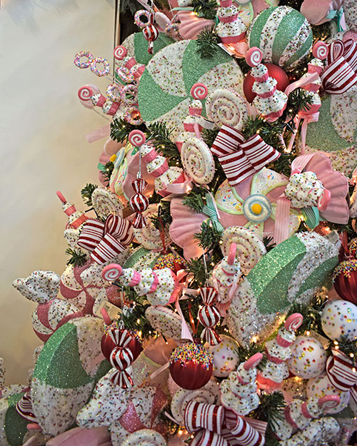 green artificial christmas tree full of sweet themed christmas decorations in pastel pink, light green, red and white stripes.