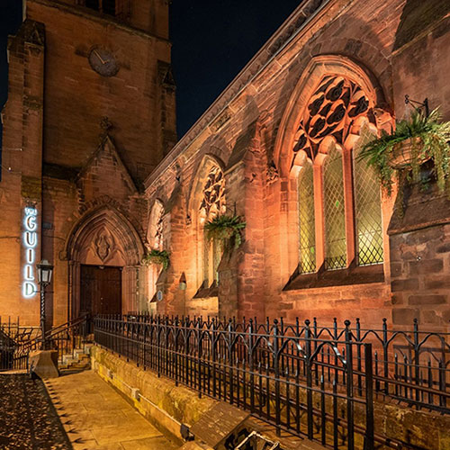 outside of the guild converted church at night with fern hanging baskets