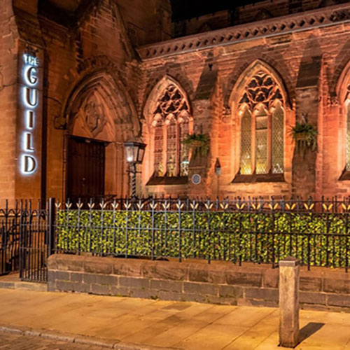close up outside of the guild converted church at night with faux hedge next to railings