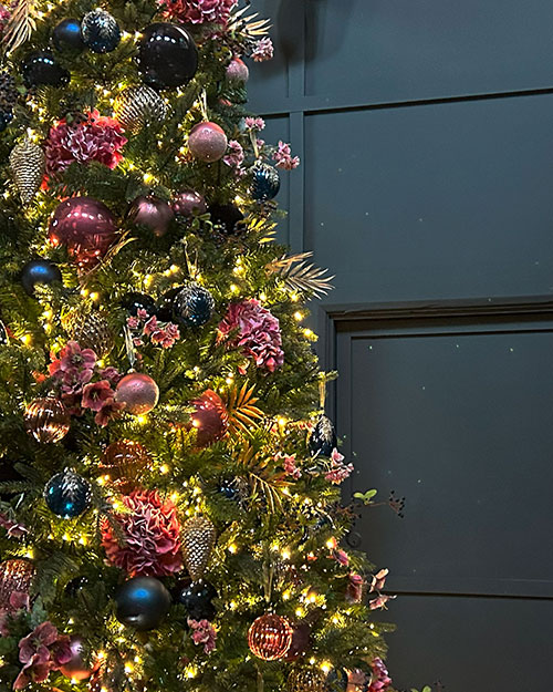 close up of large decorated christmas tree with lights next to dark panelled walls