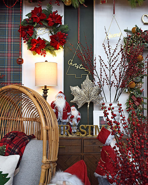 nostalgic santa ornament, poinsettia wreath, vases of berries on display with wicker chair