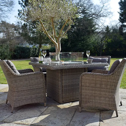 rattan garden furniture dining set with fire pit table on patio in garden