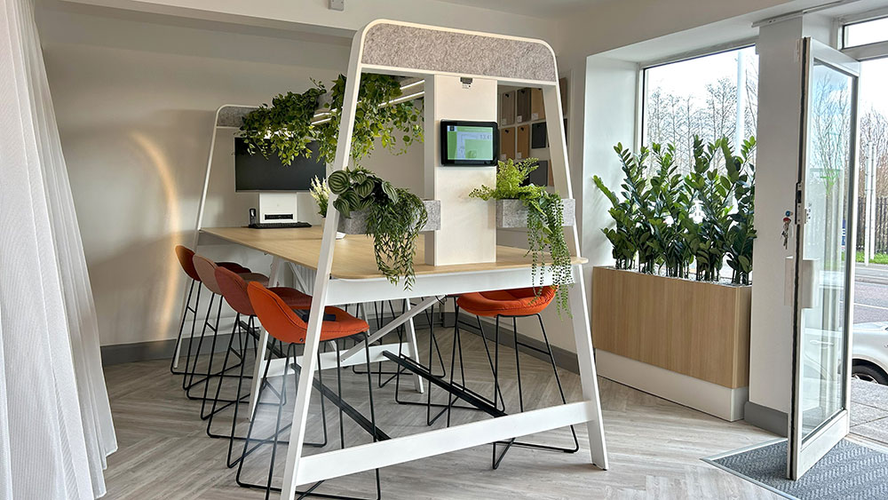 communial desk with variety of commercial faux plants and orange stools