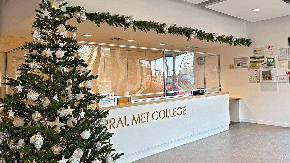 white christmas decorations on green tree and garland in wirral met college reception area