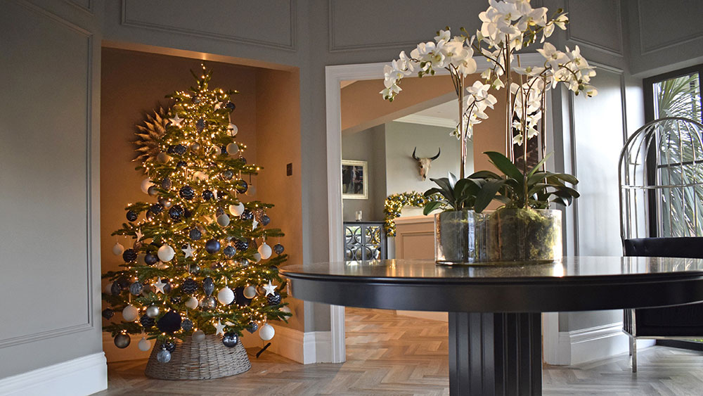 residential reception hallway with white orchid on table and Christmas tree in alcove with blue and white decorations