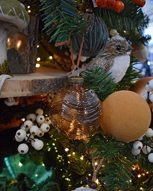 translucent orange baubale and flocked orange bauble with bird decoration and white berries and wood in christmas tree