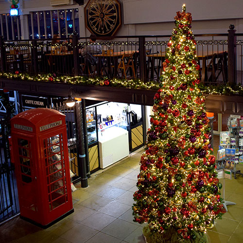 commercial 12ft Christmas tree with gold, red, green and purple decorations and red telephone box