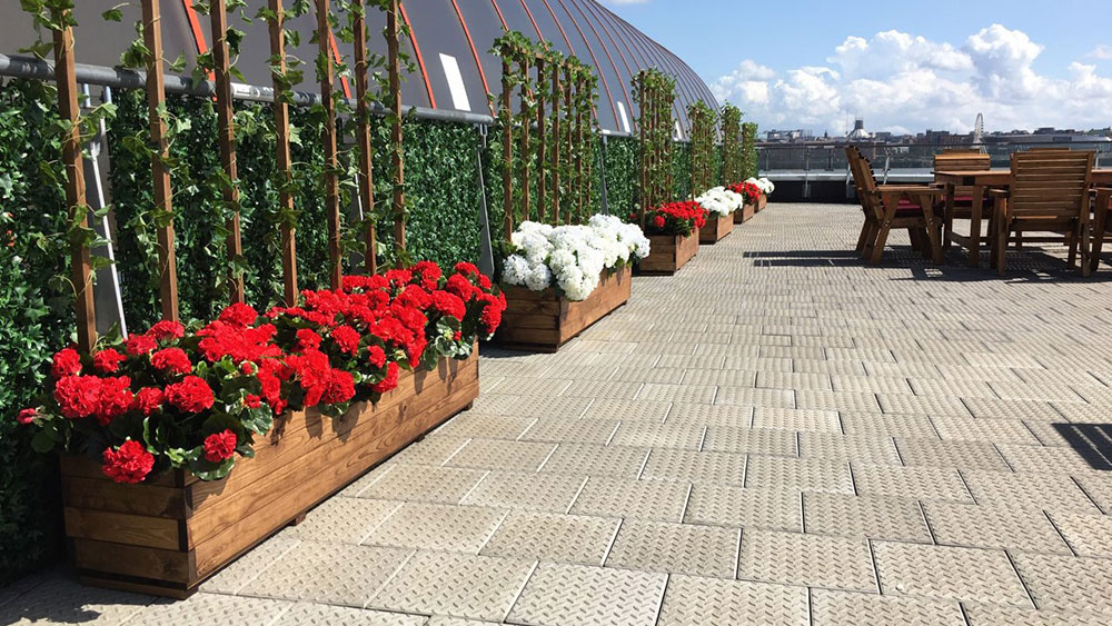 red and white outdoor fuax flower displays in wooden planters, and commerical outdoor furniture on patio