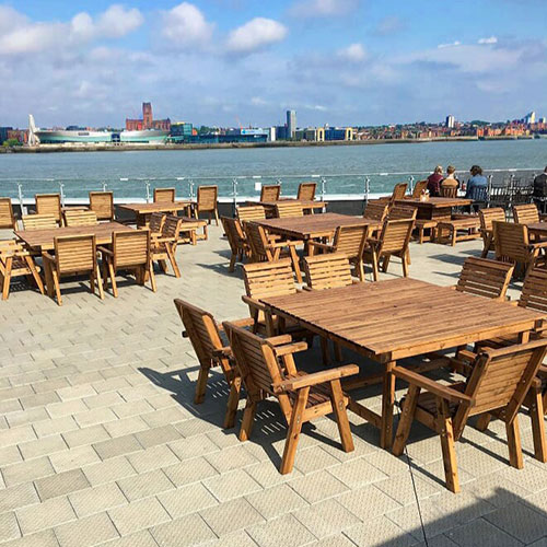 commercial wooden outdoor dining furniture on waterside terrace with view
