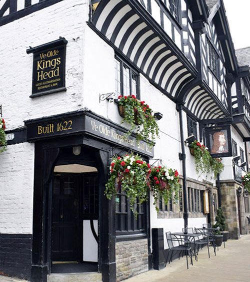century-relevant luxury faux floral displays in red and white hanging on tudor style timber pub